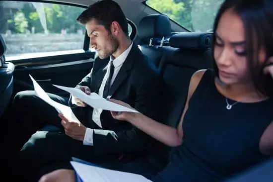 Deux personnes assises &agrave; l'arri&egrave;re de la voiture travaillant sur papier et sur ordinateur portable. Cela montre que la voiture est agr&eacute;able pour les passagers et que les personnes en retard ou voulant travailler plus vite peuvent le faire simplement. 